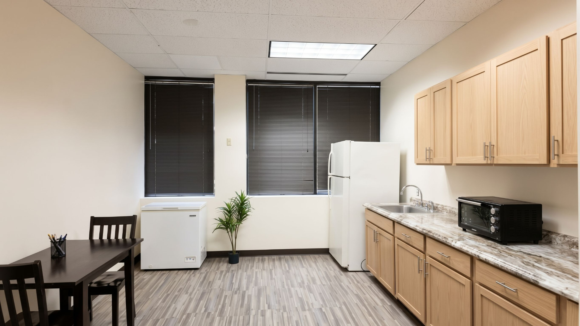 Private kitchen area with light oak cabinetry, dining table and refrigerator